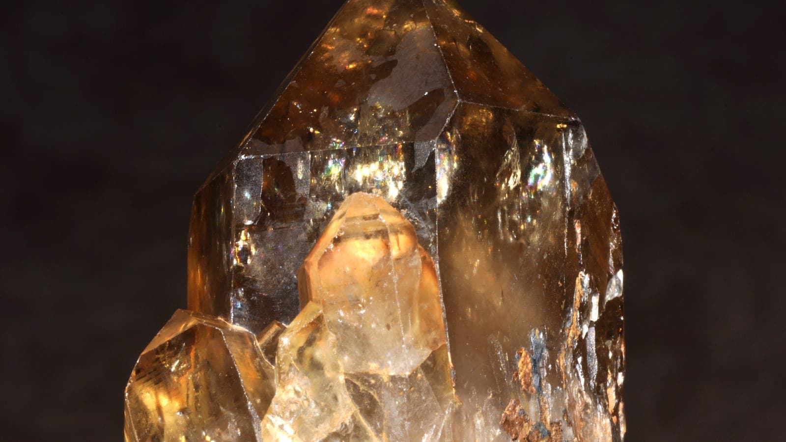 A golden citrine crystal cluster on a dark background