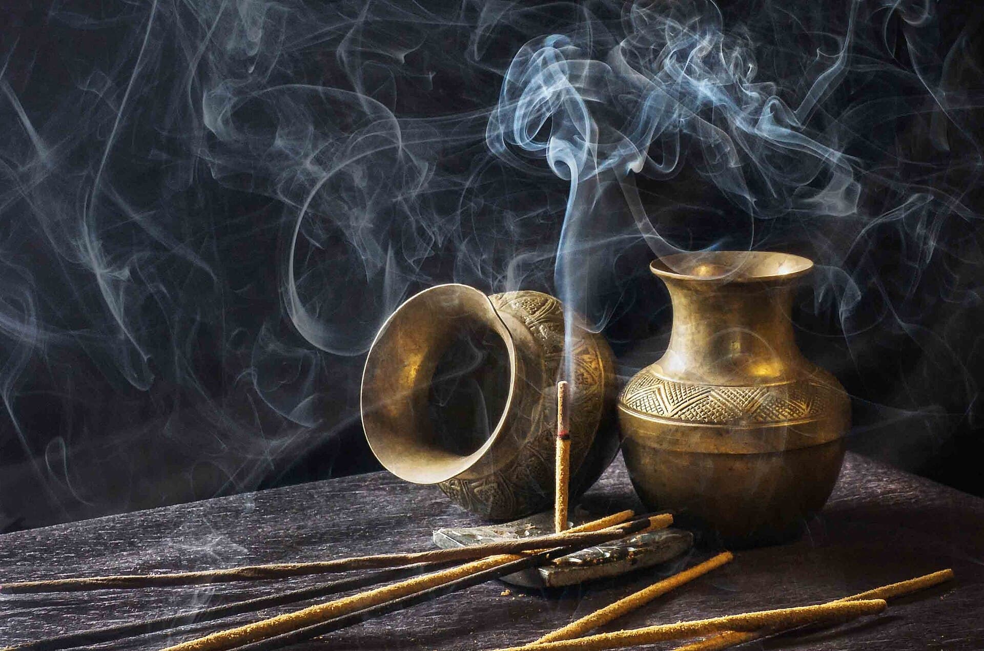Incense smoke curling around two brass vessels